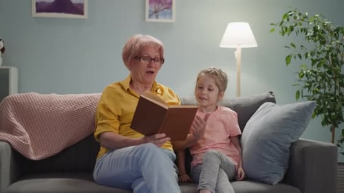 Grandmother Reads to Granddaughter on Couch