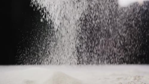 Flour Falls Down Onto Table on Black Blurred Background