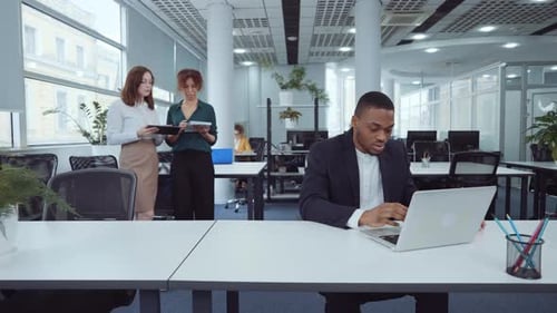 African American businessman using laptop in open space office