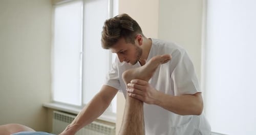 Physical Therapist Administering Leg Therapy to Patient