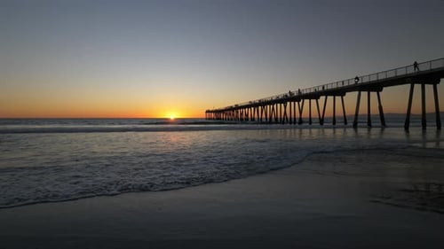 Sunset on the Beach with Pier and Silhouetted People