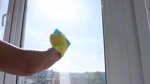 Man cleaning window with rag indoors, closeup. Camera moving