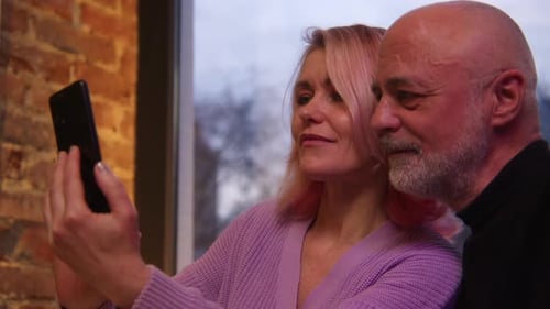 Beautiful elderly couple is photographed on date. Elderly couple takes selfie on date in cafe
