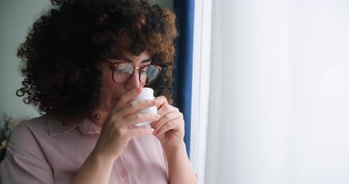 Happy Positive Woman with Curly Hair Wearing Glasses Holding Cup Enjoy Favorite Tea Drink Morning