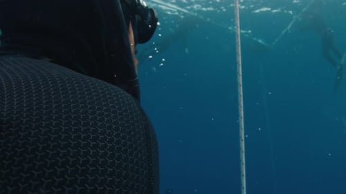 Männlicher Freitaucher, der beim Freitauchen am Seil entlang des Seils aufsteigt, trainiert im offenen Meer
