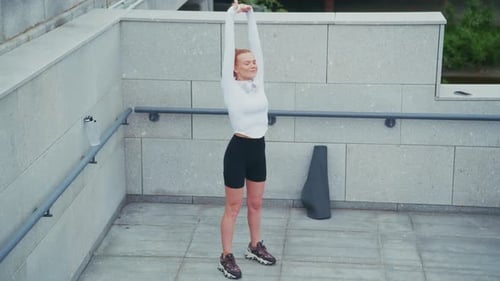 Red Haired Woman Stretching in City Environment