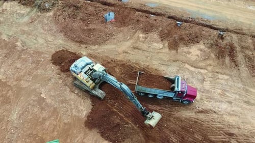 Excavator Digging Dirt into Truck Aerial View