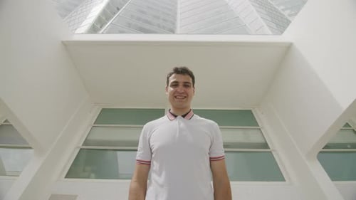 Smiling Man Puts on Headphones in the City