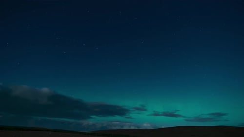 Time lapse of the aurora borealis (the northern lights) on a moonlit night with clouds passing by. F