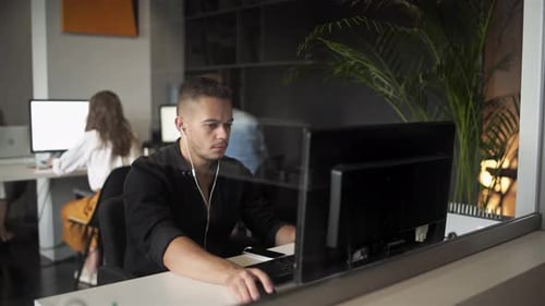 Young Businessman Discussing with Colleague Over Desktop Pc in Office