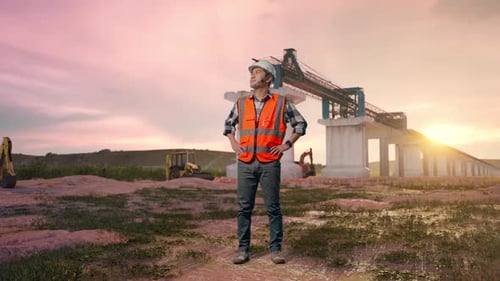 Asiatischer männlicher Ingenieur schaut sich um, während er mit Armen steht Akimbo auf der Baustelle