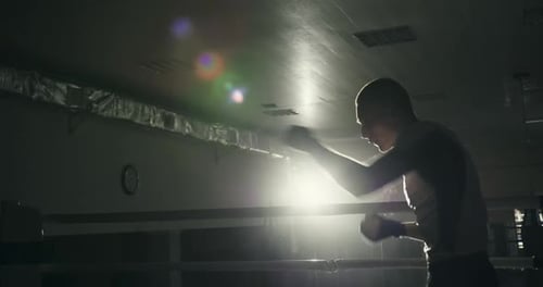 Professional Boxer Young Guy Athlete Prepares for a Fight Trains at Night in the Gym Works Out