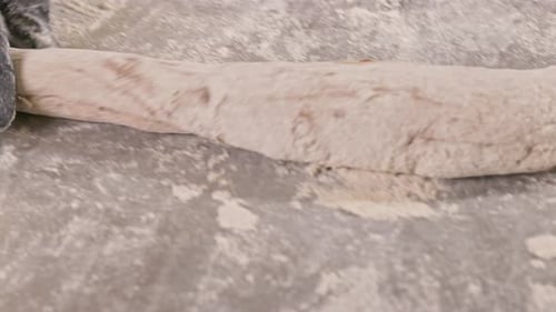 Female hands make a baguette out of dough