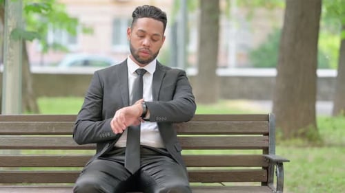 Businessman Checking Watch while Sitting on Bench