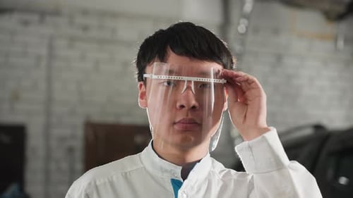 Engineer Adjusting Protective Glass in Automotive Workshop