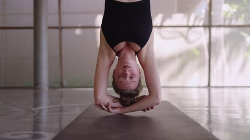 Un couple de femmes en pose de papillon inversée pratique le yoga anti-gravité dans un grand studio