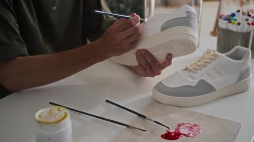 Artist Customizing White Sneakers With Teal Paint