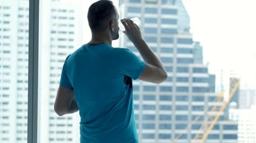 Sporty Man Exercising, Drinking Water and Admire View Form Window in Gym Active