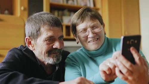 Senior Couple Looks at Cell Phone Together Indoors