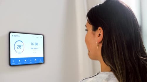 Woman interacts with smart home temperature display