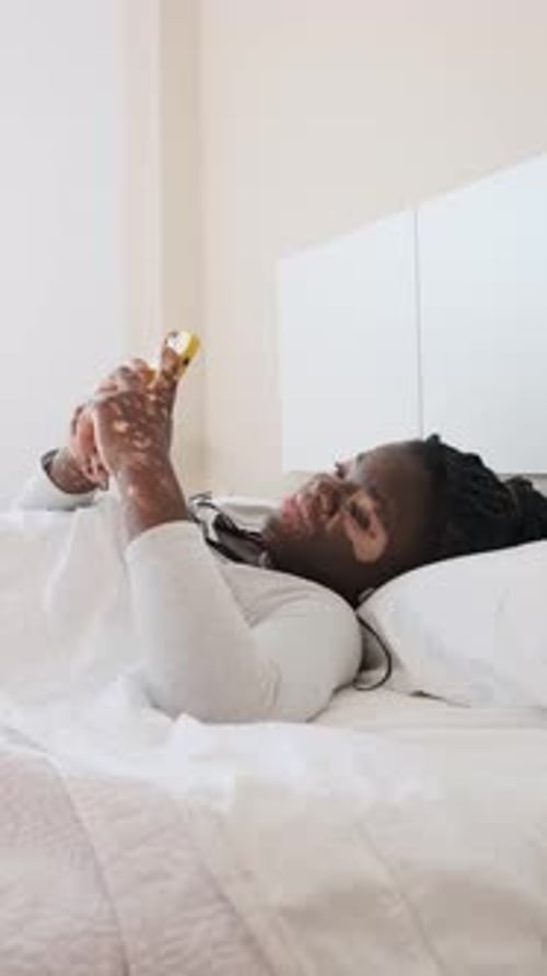 Woman Lies in Bed, Using a Smartphone