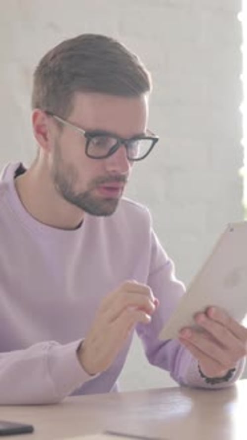 Young Man having Loss on Tablet in Office, Vertical Video