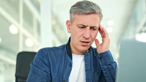 Stressed Male Worker With Headache in Modern Office