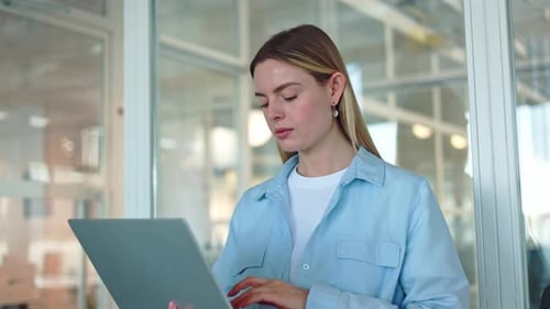 Focused Woman Working on Wireless Laptop While Standing in Middle of Office