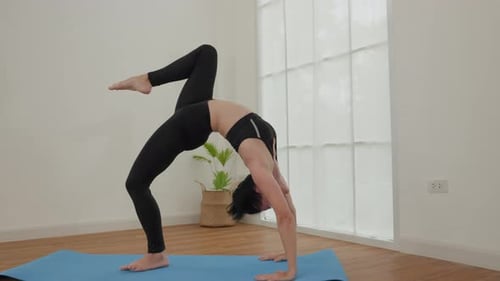 Dynamische Yoga-Pose, ausgeführt von einer Frau im Sunlit Studio