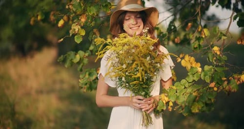 Dreamy Girl in Hat Holding Wildflowers Bouquet