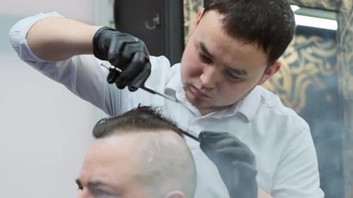 The hairdresser cuts the client's hair with scissors. A man in a beauty salon makes a cool hairstyle