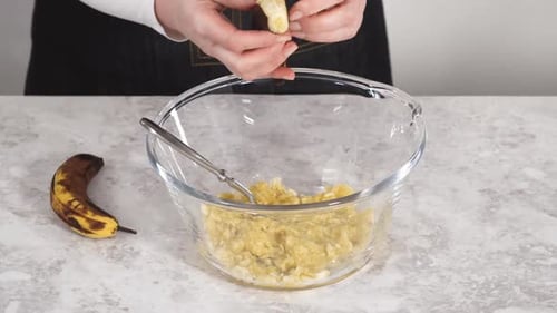 Smashing Riped Bananas in a Glass Mixing Bowl to Prepare Coconut Banana Pancakes