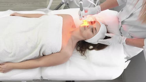 Woman Receiving Red Light Facial Treatment in Spa