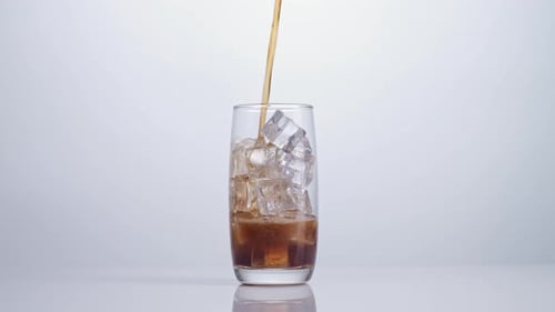 Fresh Cola Being Poured In To The Glass With Ice Cubes On White Background