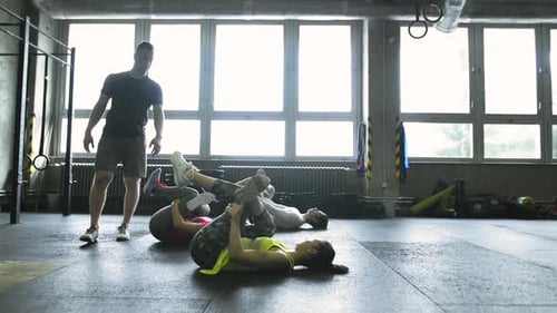 Young people stretch legs with trainer in crossfit gym for healthy lifestyle