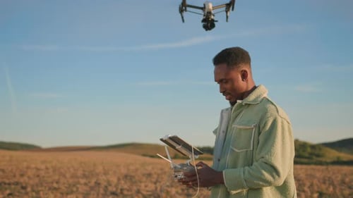 A Young Man Skillfully Operates a Drone in a Vast Field Showcasing Modern Farming