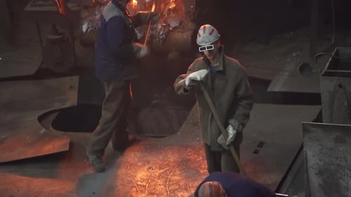 Workers Who are Engaged in Handling Molten Material in an Industrial Foundry Setting Stock Clip