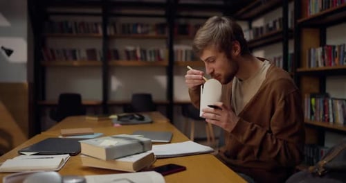 Student Eats Noodles While Studying in Library