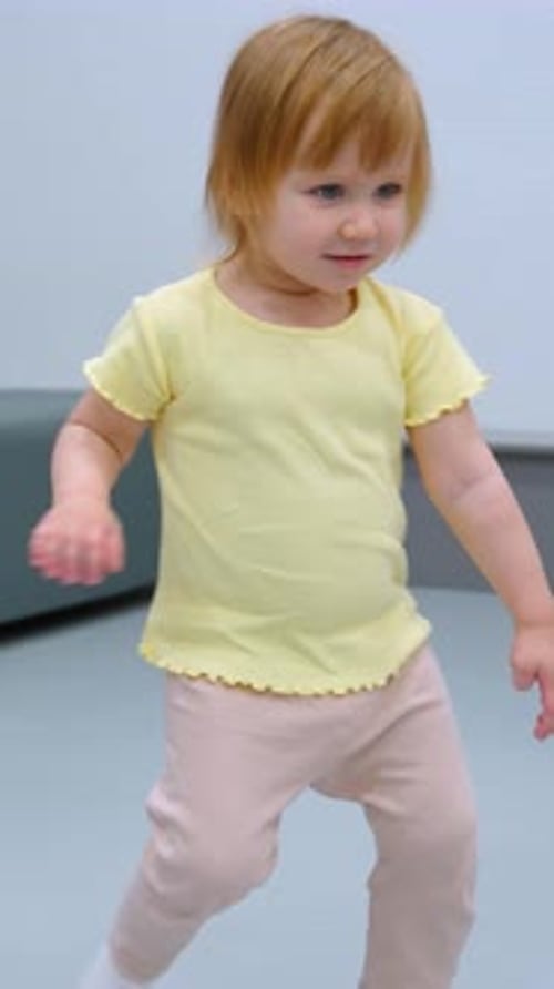 Playful Toddler Turning with Curious Expression in Modern Indoor Setting