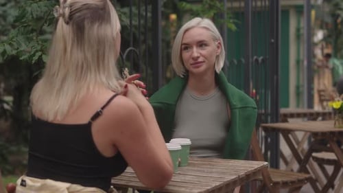 Two Women Talking and Smiling Together While Having Coffee at Outdoor Cafe