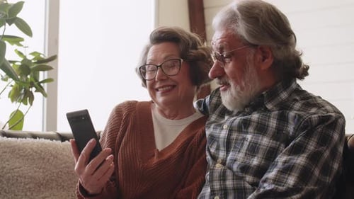 Senior Couple Enjoying Smartphone on the Sofa