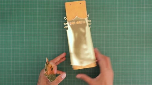 DIY craft view of hands crafting a custom gift packaging with gold coated paper on a paper container