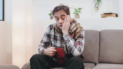 Individual Struggling with Overwhelming Emotions While Sitting on a Couch in a Cozy Living Room