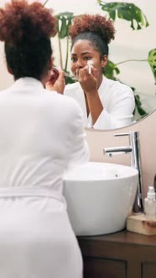 Woman Applying Makeup in Bathroom Mirror