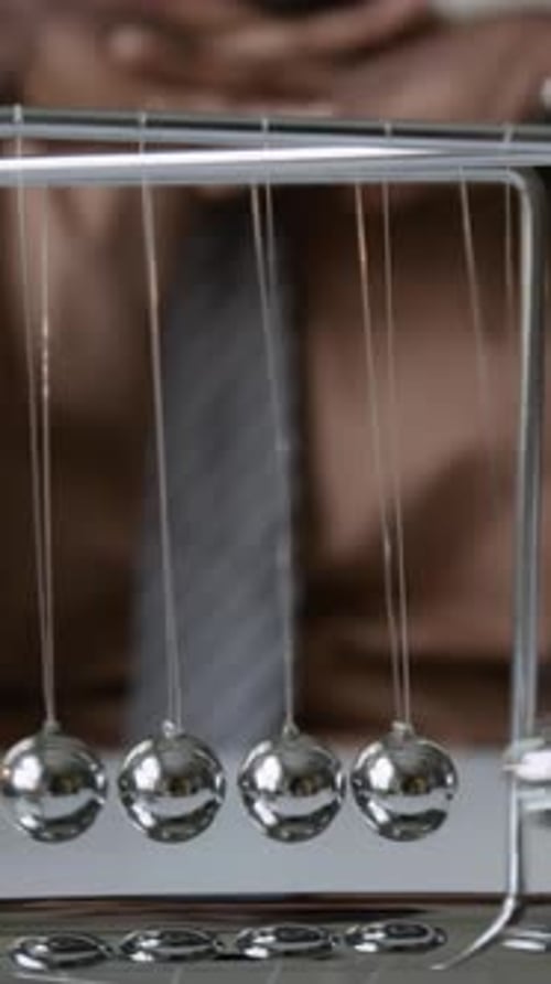 Thoughtful Man with Newtons Cradle in Office