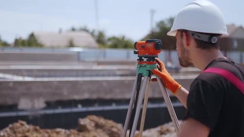 Construction Worker Uses Theodolite at Construction Site