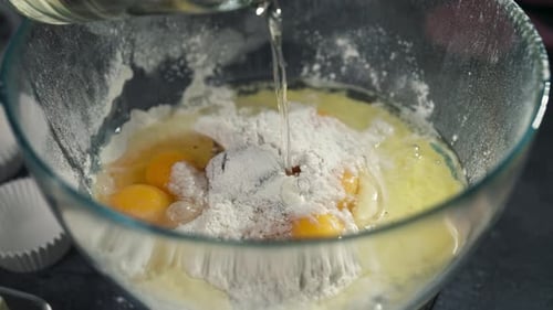 Cupcake batter mixed with oil in glass bowl, slow motion of smooth whisking