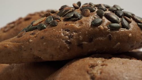 Rotating dark buns on a white background. Bakery products with grains.