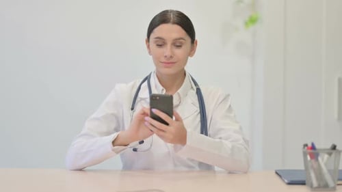Young Female Doctor Using Smartphone in Clinic