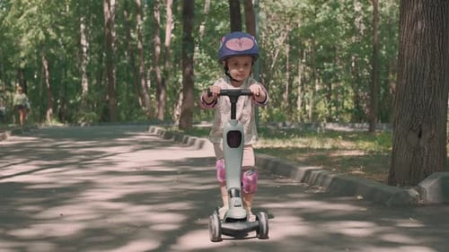 Girl 3 Years Old Rides a Scooter in Protective Clothing